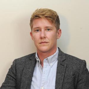 image of Alec Zuercher Reichardt in a blue button down shirt, in a dark grey blazer