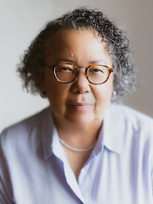 headshot of Barbara wearing glasses and a white button down shirt slightly smiling at the camera