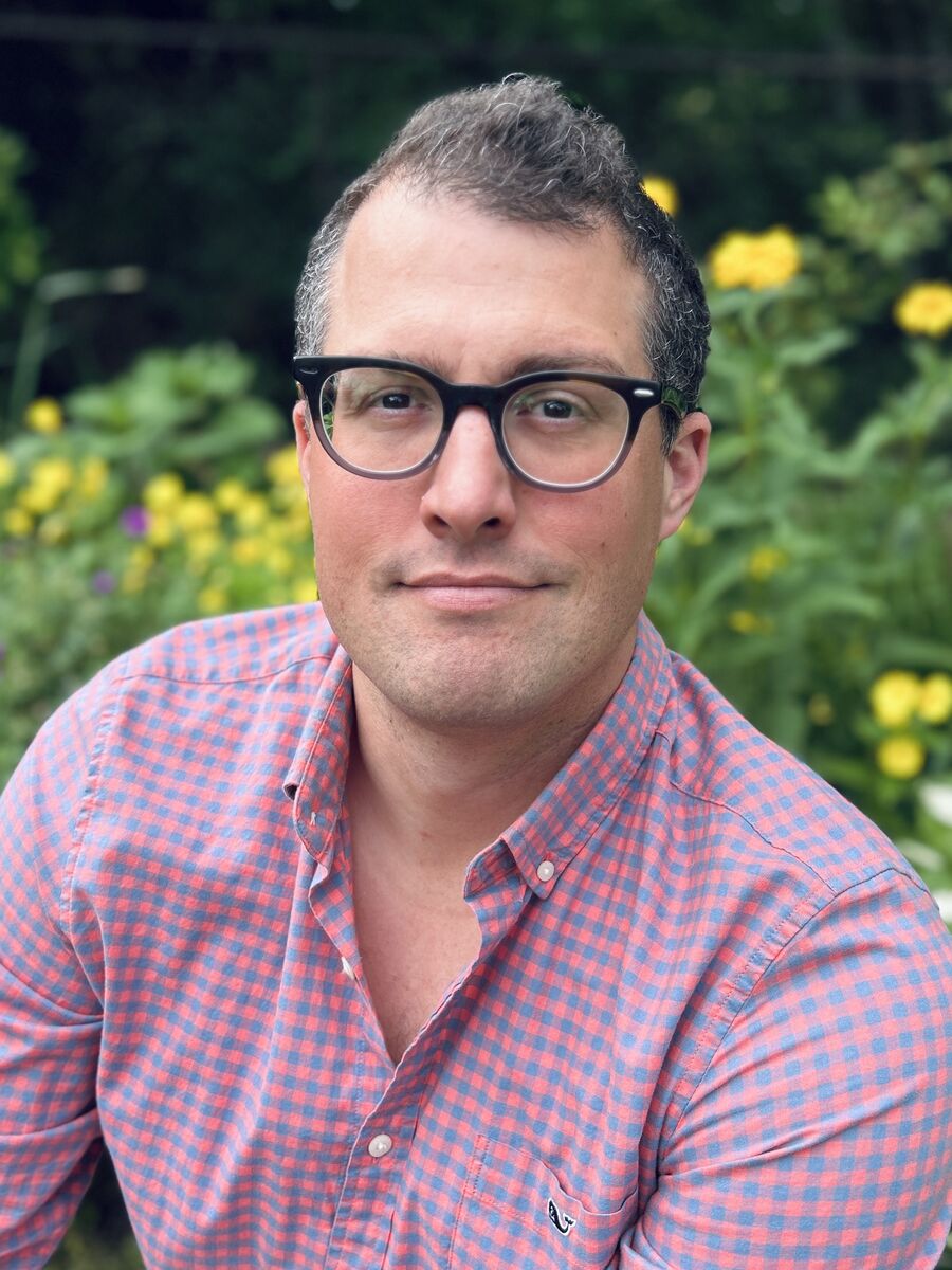 image of Asa wearing a pink button down shirt and glasses smiling at the camera