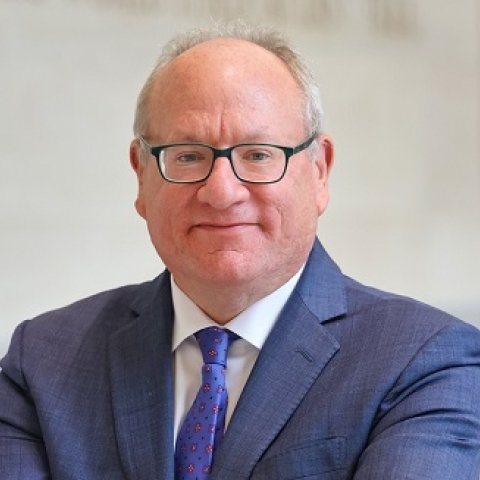 image of Michael wearing glasses and a blue suit smiling at the camera