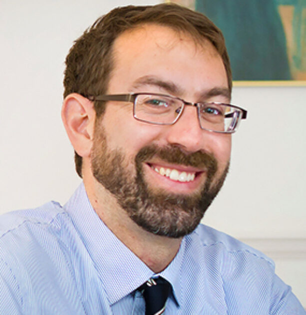 The photo is a headshot of Dr. Samuel Moyn wearing a blue shirt with a tie and glasses.