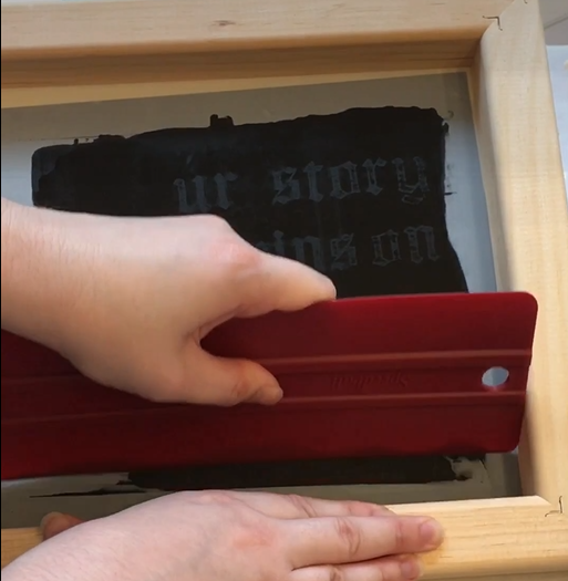 Hand using screenprinting tools.