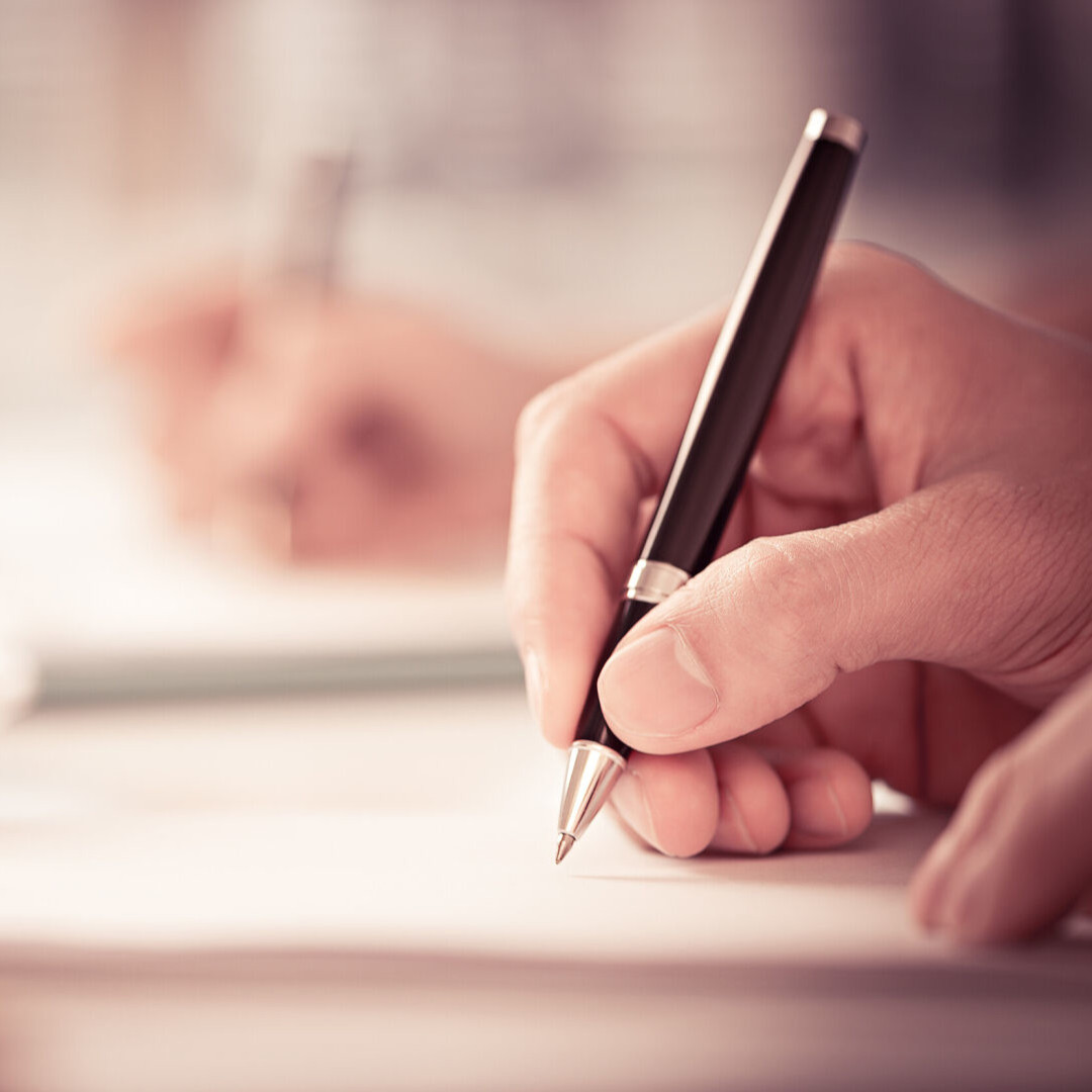 A hand writing with a pen