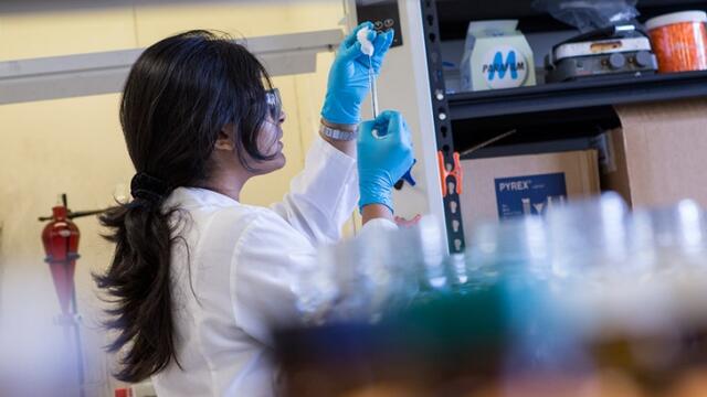 A female researcher cleaning a syringe in a lab.