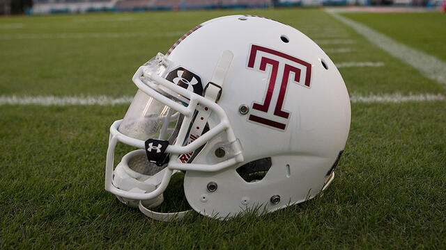 A white Temple football helmet with a cherry Temple