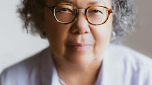 headshot of Barbara wearing glasses and a white button down shirt slightly smiling at the camera