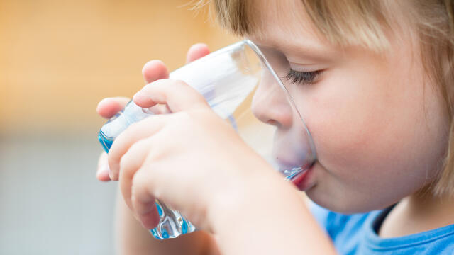 a toddler drinking a glass of water
