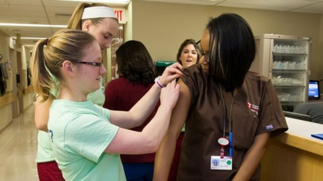 A member of the Flu Crew applying a bandage to an employee after a vaccination.