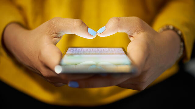 Hands typing on a cell phone.