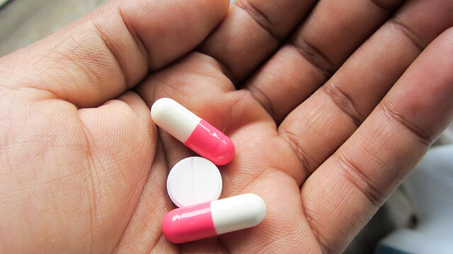 A hand holding three pills.