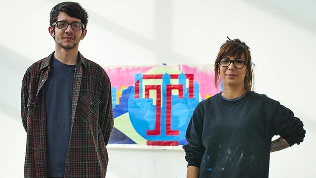 A man and woman standing in front of a painting.