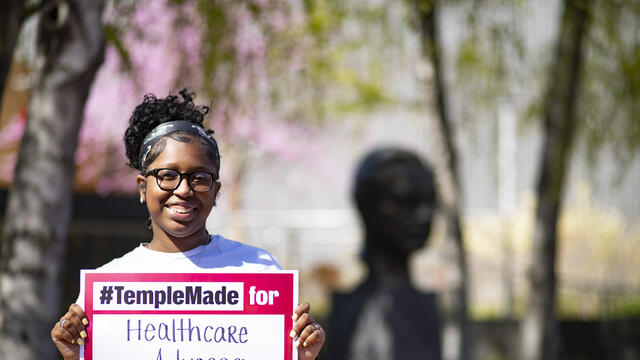  Image of India Byrd standing outside holding up a Temple Made for sign. 