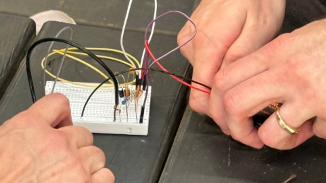Hands building a transmitter.