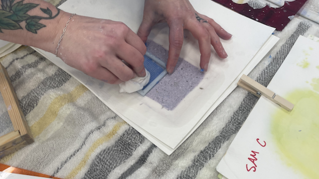 Hands working with a screen on a piece of paper.