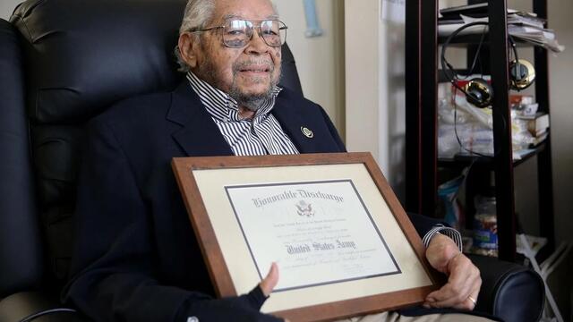 Nelson Henry Jr. holding his honorable discharge certificate.