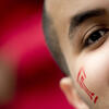 A close up of a man with a red Temple T painted on his face.
