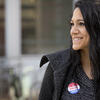 A woman smiling with an I voted sticker on her shirt.