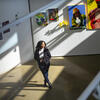 Image of Taylor Sanders standing in front of various paintings.