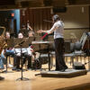 Image of Matthew Levy soloing with the wind symphony. Patricia Cornett conducts while Emma O'Halloran observes.