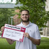 Ezekiel Cartwright standing outside holding up a Temple Made for sign