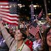 Attendees waving American flags in the crowd of the Democratic National Convention.