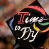 A Temple graduate triumphantly raising his cap at commencement.