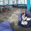 A female student sitting in a blue chair in the refurbished Owls Nest.