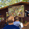 A man outside showing students a large map of the world.